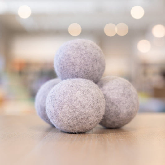 Four grey, Wool Dryer Balls stacked on top of each other on counter