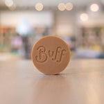 Rhassoul Clay Face Bar by Buff City Soap on wooden surface with blurred background